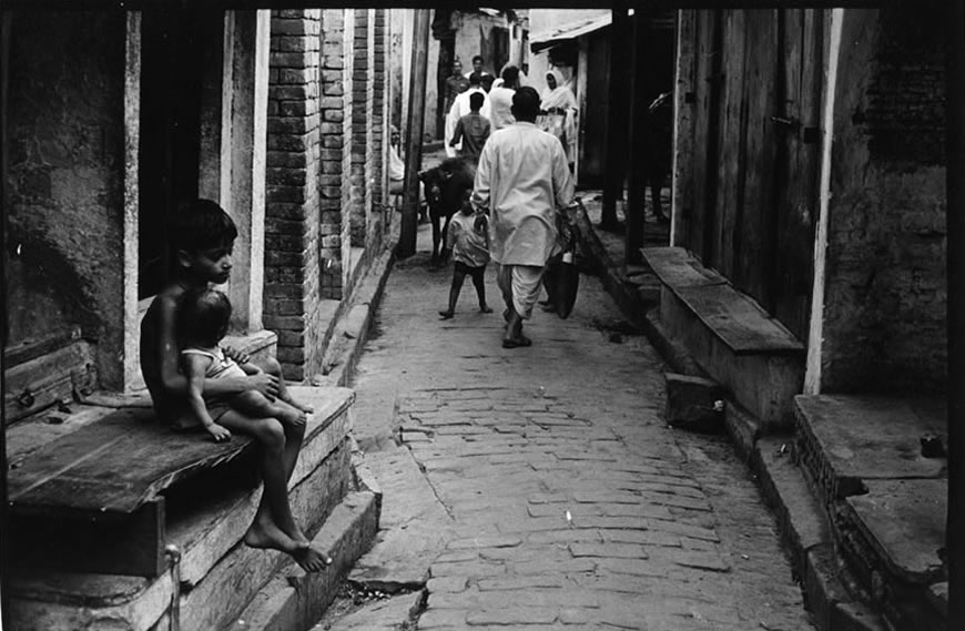Boy holding baby while sitting on steps on a narrow street (Мальчик держит ребёнка на руках, сидя на ступеньках на узкой улочке), 1970