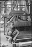 Мальчик на корточках у ткацкого станка