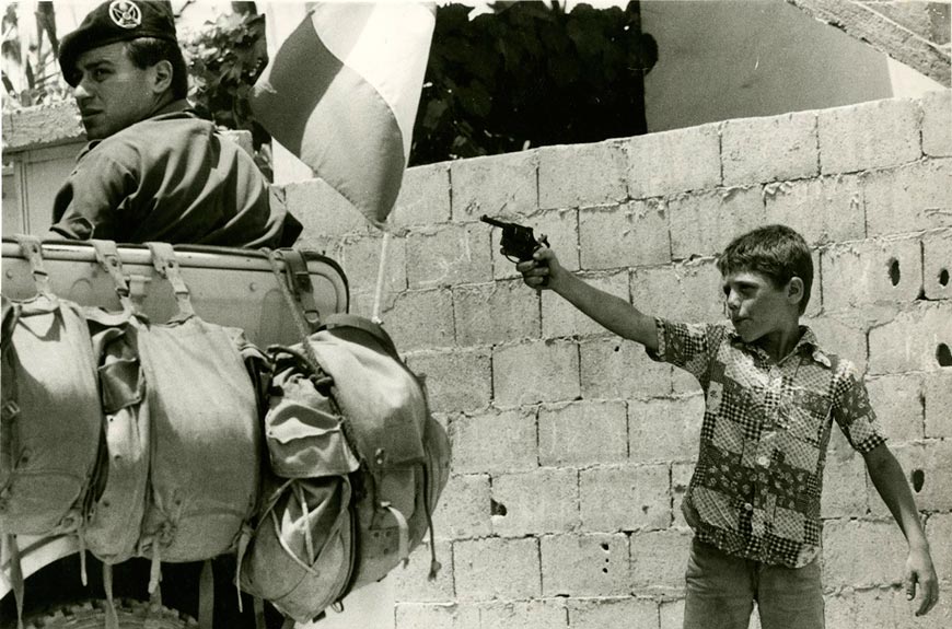 A young boy aiming toy gun at passing Italian patrol (Мальчик целится игрушечным пистолетом в проезжающий итальянский патруль), August 1983