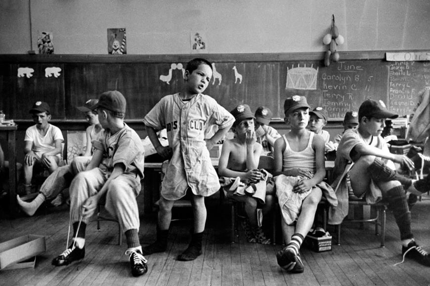 A group of Boys Club little league baseball players put on their uniforms while sitting in a classroom (Группа игроков Бойc-клуба Малой бейсбольной лиги надевает форму в классе), 1954